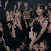 a group of women in black dresses are posing for a photo with their hands in the air