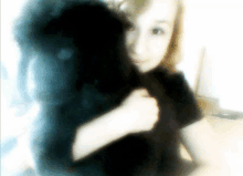 a girl holds a black dog in her arms