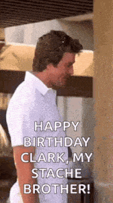 a man in a white shirt is standing next to a wall and says happy birthday clark , my stache brother .