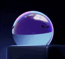 a purple and blue ball with a face on it is sitting on a table .