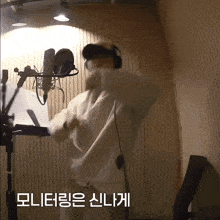 a man wearing headphones and a mask stands in front of a microphone in a room with korean writing on the wall