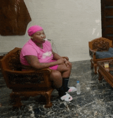 a woman in a pink shirt sits in a chair with her legs crossed