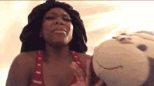 a woman in a red tank top is holding a stuffed animal in front of her face