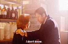 a man and a woman hugging in front of a sign that says " i do n't know "