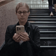 a woman with a stethoscope around her neck is sitting on stairs looking at her phone