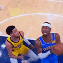 two men are playing basketball on a court and one of them is holding the ball .