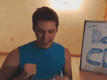 a man in a blue tank top stands in front of a white board that says geeky