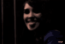 a close up of a woman 's face in a dark room smiling .