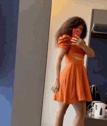 a woman in an orange dress is taking a selfie