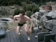 a shirtless man in underwear is jumping into a pool .