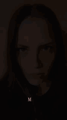 a close up of a woman 's face with the letter m on the bottom right