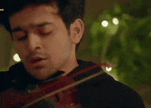 a man playing a violin with arabic writing on the bottom left