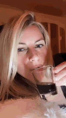 a woman is drinking a glass of water .