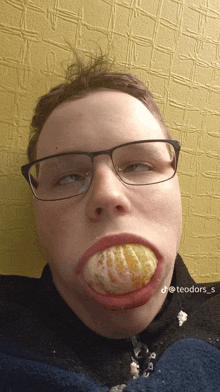 a man with glasses and a tangerine in his mouth has the hashtag teodor s on the bottom right