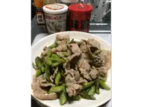 a plate of meat and asparagus next to a jar of seasoning with chinese writing on it
