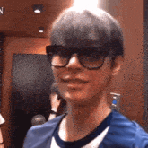 a young man wearing glasses and a blue shirt is standing in an elevator