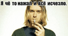 a man with long blonde hair is smoking a cigarette in front of a white background with russian writing on it