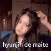 a girl with long hair is holding her hair in a ponytail with the words hyunjin de maite written below her .