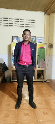 a man in a suit and pink shirt stands in a room