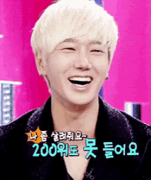 a man with blonde hair is smiling in front of a pink background with chinese writing on it