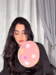 a woman blowing up a pink polka dot balloon with the word zeuoigifs on the bottom