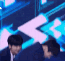 a blurry picture of two men standing next to each other on a stage with a blue background .