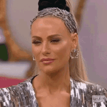 a woman wearing a headband and earrings is standing in front of a mirror .