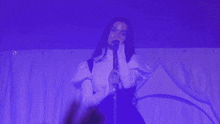 a woman in a white shirt is singing into a microphone on a stage .