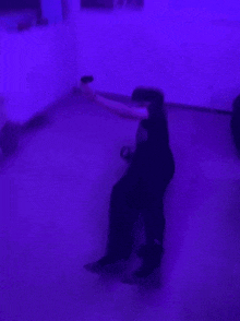 a blurry picture of a person playing a video game in a living room with purple lights .