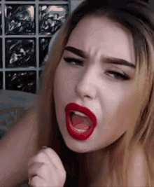 the woman is wearing red lipstick and making a funny face .