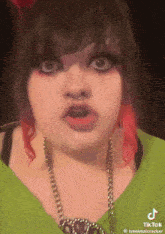 a woman with a green shirt and red hair is making a funny face .