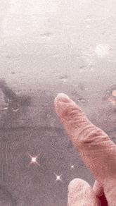 a person 's finger is pointing at a rainy window .
