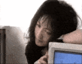 a woman leaning on a computer monitor with her head on it