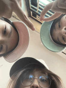 three people wearing hats and glasses are looking down