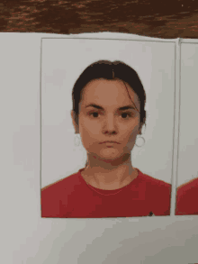 a woman wearing a red shirt and hoop earrings looks at the camera