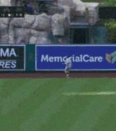 a baseball player throws a ball in front of a memorial stadium banner