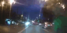 it is a blurry picture of a car driving down a city street at night .