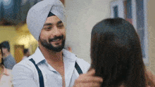 a man in a turban is hugging a woman in a room .