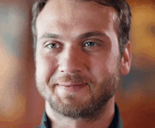 a close up of a man 's face with a beard and blue eyes .