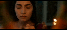 a woman is holding a candle in her hand and looking at it .
