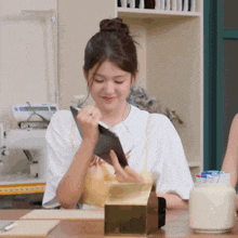 a woman in a white shirt is sitting at a table looking at a book