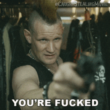 a man with a mohawk pointing a gun with the words you 're fucked underneath him