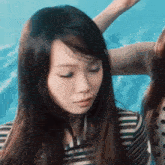 a woman in a striped shirt with her eyes closed