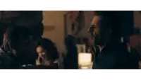 a man with a beard talking to another man in a dark room