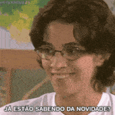 a woman wearing glasses and a white shirt is smiling and saying ja estao sabendo da novidade .