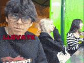 a man wearing glasses and a black shirt that says llevate