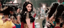 a woman in a red saree is dancing in a crowd .