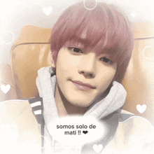 a man with pink hair is laying on a couch with hearts around him and the words somos solo de mati
