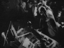 a black and white photo of a man playing a piano