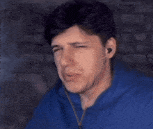 a man in a blue hoodie smoking a cigarette with smoke coming out of his mouth